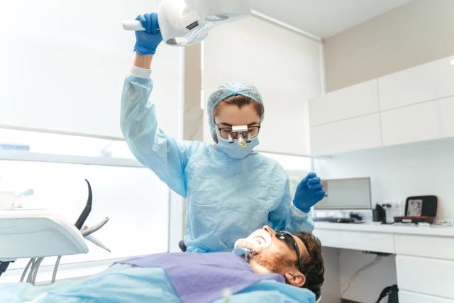Dentist adjusting a dental light over a patient.