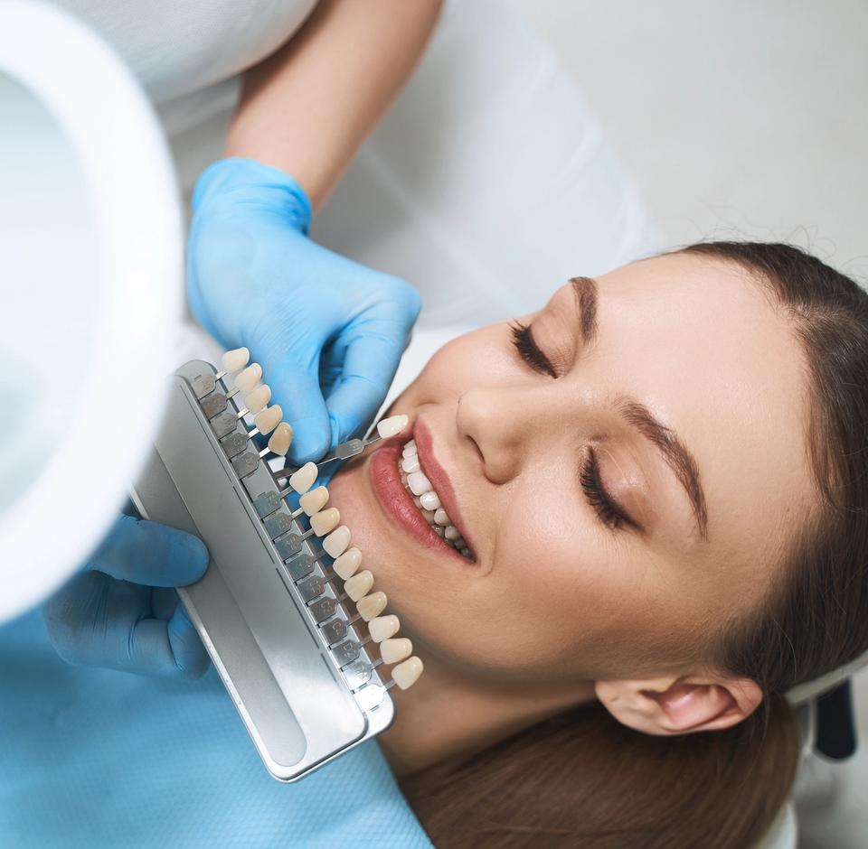 a woman is sitting in a dental chair while a dentist examines her teeth with a magnifying glass .