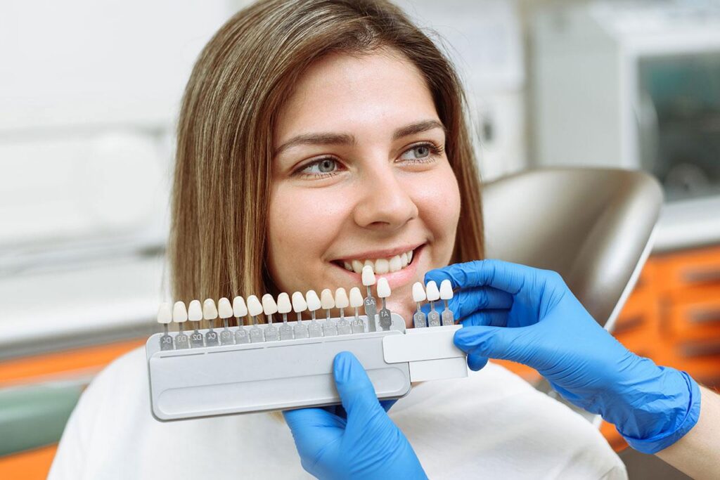 a woman is sitting in a dental chair while a dentist examines her teeth .