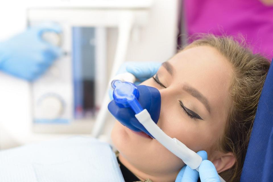 Patient wearing a blue nasal mask for sedation with eyes closed.